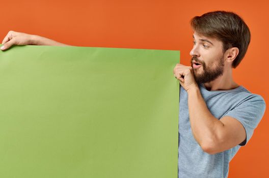 bearded man holding a green banner design orange background. High quality photo