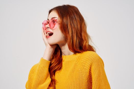 beautiful woman in a yellow sweater hairstyle fashion glasses light background. High quality photo