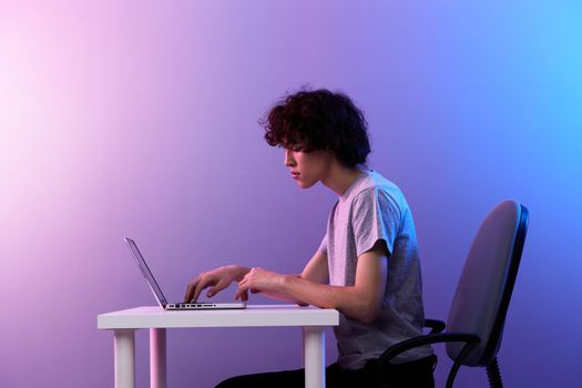 curly guy sitting at the table gaming laptop Lifestyle technology. High quality photo