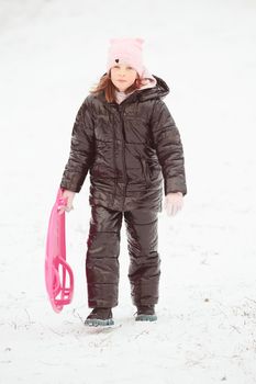 Active girl sliding down the hill. Happy child having fun outdoors in winter on sledge. Family time