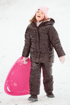 Active girl sliding down the hill. Happy child having fun outdoors in winter on sledge. Family time