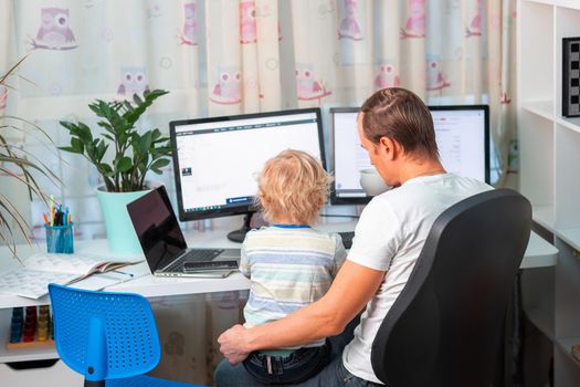 Father with kid trying to work from home during quarantine. Stay at home, work from home concept during coronavirus pandemic