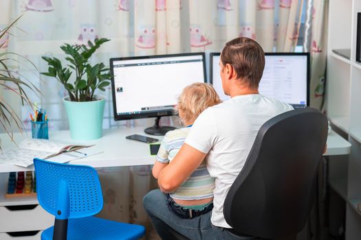 Father with kid trying to work from home during quarantine. Stay at home, work from home concept during coronavirus pandemic