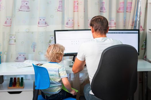 Father with kid trying to work from home during quarantine. Stay at home, work from home concept during coronavirus pandemic