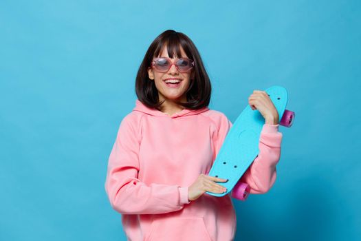 woman in sunglasses with a skateboard blue background. High quality photo