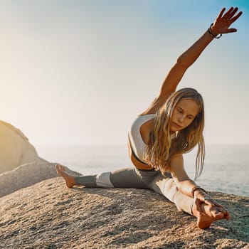 Shot of an athletic young woman practicing yoga on the beach