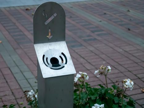 Modern cigarette metallic trash bin in the street, outdoors. Stainless steel litter bin, with a ashtray. Outdoor smoking area zone