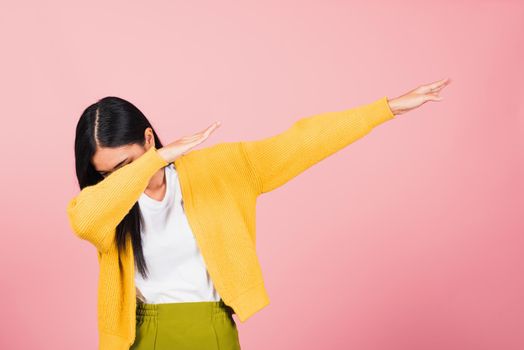 Asian happy portrait beautiful cute young woman teen smile standing move showing DAB dance against gesture raise hands arms covering  face isolated, studio shot on pink background with copy space