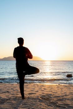 Health and wellness. Young healthy woman practicing yoga on the beach at sunset