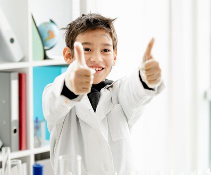 School boy showing super with hands during chemistry experiment in elementary science class. Clever pupil kid in lab