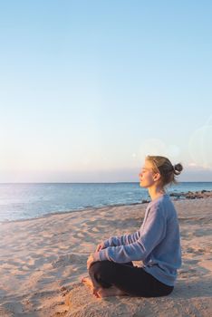 Health and wellness. Young healthy woman practicing yoga on the beach at sunset