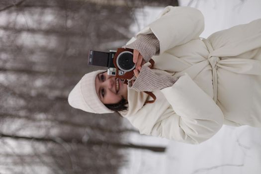 a girl with a camera in her hands against the background of a winter landscape