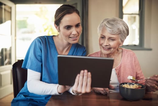 Shot of a young nurse and senior woman using a digital tablet at breakfast time in a nursing home