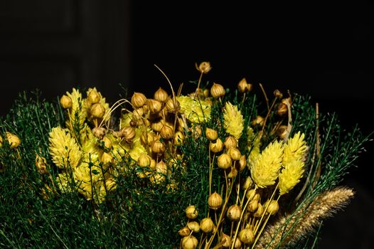 A wintry floral arrangement of dried small flowers, buds and branches.