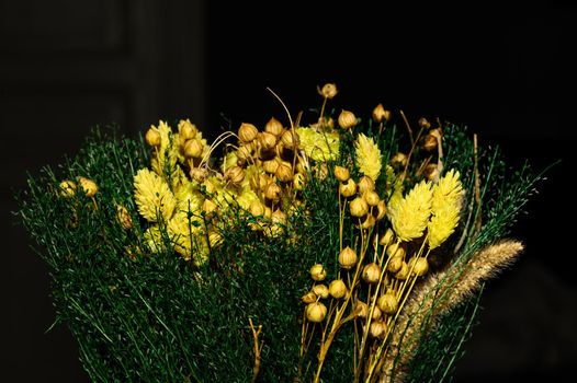 A wintry floral arrangement of dried small flowers, buds and branches.