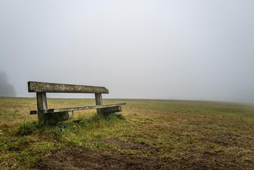 An old bench stands on a hill shrouded in fog and invites you to rest.