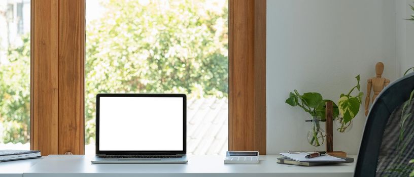 Blank screen laptop computer in minimal office room with calculatpr and decorations and copy space