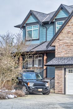 Fragment of residential house on winter season in Canada with black car parked in front