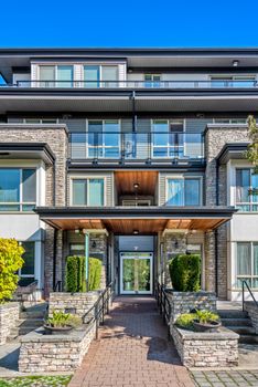 Entrance of residential apartment building with paved pathway in front.