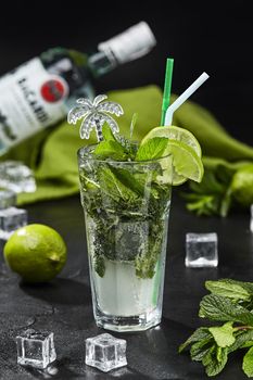 Traditional Cuban refreshing Mojito cocktail based on white rum with sugar syrup, lime juice, soda water and spearmint server with crushed ice in highball glass on black background