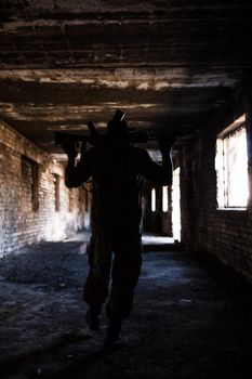 Silhouette of a soldier with weapons in a war in ruins