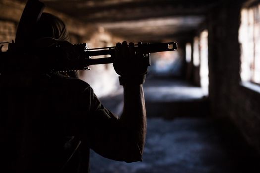 Silhouette of a soldier with weapons in a war in ruins