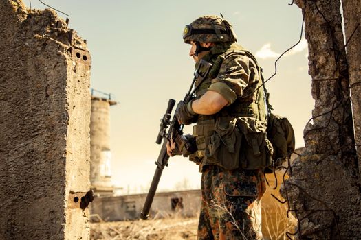 young soldiers with guns, A soldier in equipment and with arms inspects a ruined house outside the city.