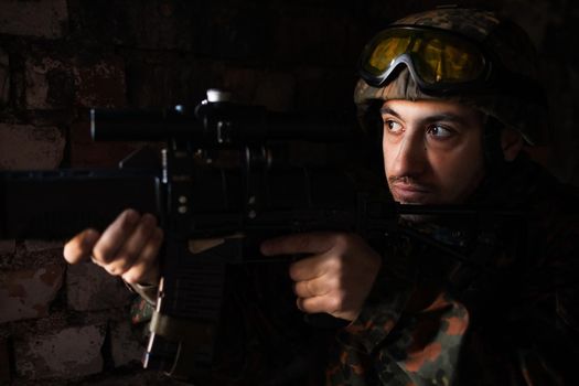 young soldiers with guns, A soldier in equipment and with arms inspects a ruined house outside the city.
