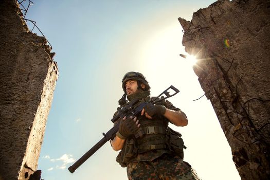 young soldiers with guns, A soldier in equipment and with arms inspects a ruined house outside the city.