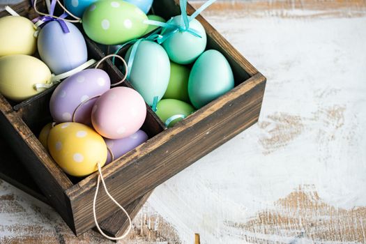 Box full of colorful eggs on rustic background