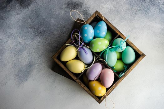 Box full of colorful eggs on rustic background