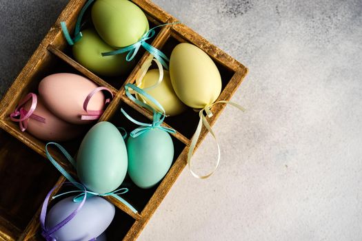 Box full of colorful eggs on rustic background