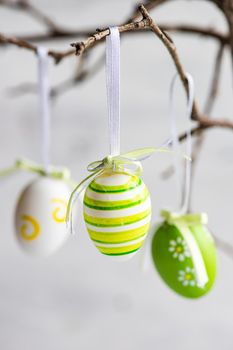Easter card with tree branches decorated with eggs on white rustic background