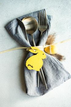 Minimalistic table setting with grey napkin and cutlery decorated with wooden bunny