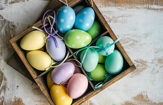 Box full of colorful eggs on rustic background