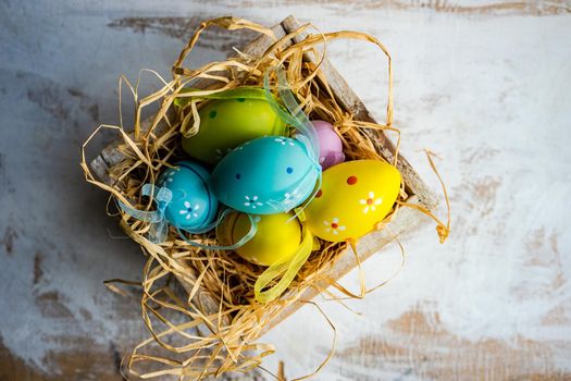 Box full of colorful eggs on rustic background