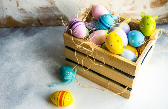 Box full of colorful eggs on rustic background