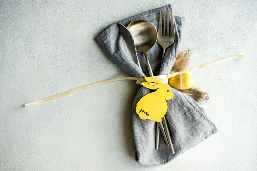 Minimalistic table setting with grey napkin and cutlery decorated with wooden bunny