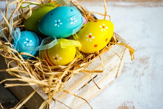 Box full of colorful eggs on rustic background