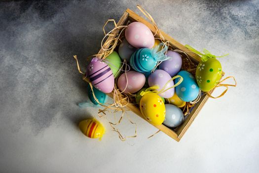 Box full of colorful eggs on rustic background