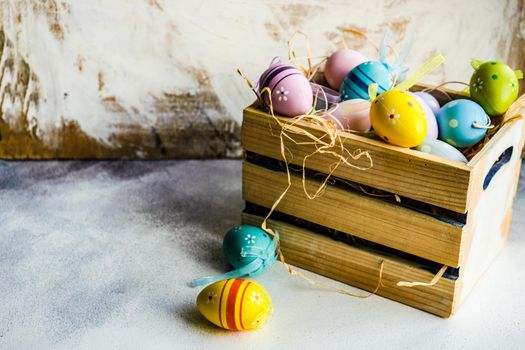 Box full of colorful eggs on rustic background