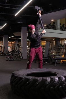 A man hits a sledgehammer wheel in fitness, the concept of a healthy lifestyle male sledgehammer active hit sport, for strength exercise for adult for bodybuilder wheel, strike ethnic. Club energy ethnity, strenght