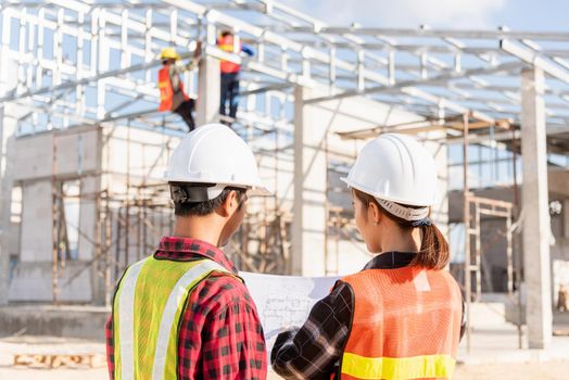 Back two architect and client discussing help create plan with blueprint home building at construction site. Asian engineer foreman worker man and woman meeting talking on drawing paper project