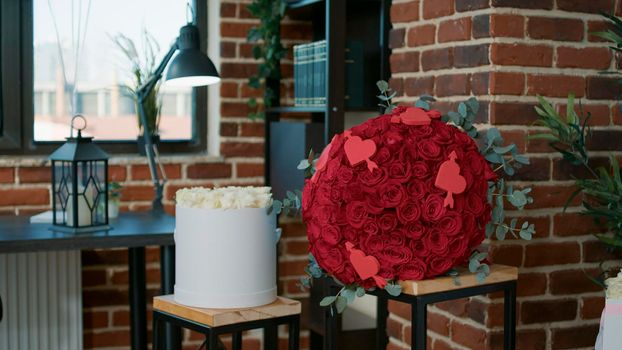 Empty living room with nobody in it decorated by boyfriend with red roses and holiday gift to surprise girlfriend during valentine day event. Concept of romance anniversary. Romantic design at home