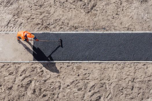 Laying worker new asphalt paving road construction site work pathway. New road construction worker laying asphalt surface on walkway work path. Sidewalk construction asphalt work tarmac road worker