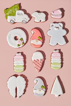 Colorful gingerbreads of different shapes with sugar icing on pinkish background. Traditional Christmas cookies.Top view, flat lay