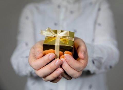 Hands holding gold gift box isolated on gray background. giving present, Birthday,Christmas,Mothersday other Holiday with copy space space for text