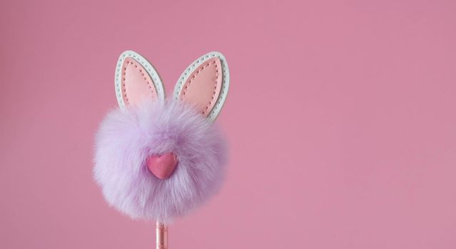 Cute little fluffy lilac bunny toy on pink background. Easter Concept.