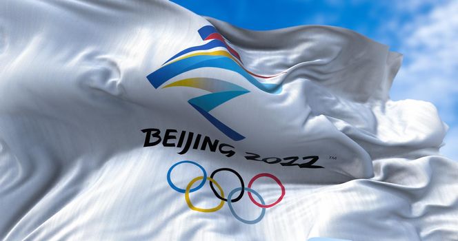 Beijing, CHN, Jan. 2022: Beijing 2022 flag waving in the wind with the Olympic flag blurred in the foreground. Beijing 2022 winter olympics games are scheduled to take place from 4 to 20 February 2022