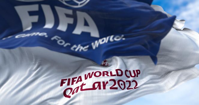 Doha, Qatar, January 2022: Flags with FIFA and Qatar 2022 World Cup logo waving in the wind. The event is scheduled in Qatar from 21 November to 18 December 2022